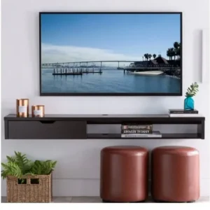 میز تلویزیون مدل میوا AVI-TVT032 دیواری یک کشو محصولی مدرن و مینیمال است که با طراحی دیواری خود، فضای نشیمن را به شکلی منظم و زیبا جلوه می‌دهد. این میز تلویزیون با رنگ چوب تیره و خطوط صاف، به‌راحتی با انواع دکوراسیون داخلی هماهنگ شده و ظاهری لوکس به محیط می‌بخشد. ساختار دیواری میز علاوه بر زیبایی بصری، موجب صرفه‌جویی در فضا و افزایش نظم محیط می‌گردد. متریال MDF با کیفیت بالا تضمین‌کننده دوام و مقاومت میز در برابر فشار، رطوبت و تغییرات دما است. وجود یک کشوی کاربردی با ریل فلزی روان، امکان نگهداری تجهیزات جانبی، ریموت یا دفترچه‌ها را در  میز تلویزیونی فراهم می‌سازد. طراحی ساده اما کاربردی این محصول باعث شده که در خانه‌های مدرن جایگاه ویژه‌ای پیدا کند. نمای مات و ضدخش سطح میز، نگهداری آسان را ممکن کرده و موجب حفظ کیفیت در طول زمان می‌شود. اگر به دنبال میز تلویزیونی دیواری شیک و کاربردی هستید، این مدل با یک کشوی مخفی بهترین انتخاب خواهد بود.  ویژگی‌های محصول ساخت MDF متراکم با کیفیت بالا طراحی دیواری برای صرفه‌جویی در فضا دارای کشو با ریل فلزی نرم رنگ‌بندی تیره و مدرن سطح ضدخش با نگهداری آسان مناسب برای فضاهای کوچک و بزرگ هماهنگ با تلویزیون‌های صفحه تخت طراحی بدون پایه برای جلوه مینیمال نصب آسان و ایمن بر روی دیوار دارای فضای بالا برای تزئینات یا گلدان نقاط قوت محصول افزایش نظم و کاهش شلوغی فضا ظاهری شیک و مدرن با رنگ تیره مناسب برای سبک‌های معاصر و مینیمال استفاده از متریال بادوام و مقاوم صرفه‌جویی در فضا و کاربرد بالا قابلیت ترکیب با المان‌های تزئینی کشوی روان برای استفاده روزمره وزن سبک نسبت به استحکام بالا نصب سریع بدون نیاز به ابزار خاص افزایش زیبایی و نظم محیط داخلی