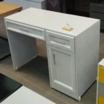 میز تحریر مدل ایکات AVI-DE037   سفید با دو کشو و درب‌دار  MDF یک انتخاب هوشمندانه برای افرادی است که به طراحی مینیمال، فضای ذخیره‌سازی و کیفیت ساخت اهمیت می‌دهند. این میز با رنگ سفید آرامش‌بخش و ظاهر ساده و شیک، به راحتی با انواع دکوراسیون داخلی هماهنگ می‌شود. سطح اصلی از MDF با تراکم بالا ساخته شده که در برابر فشار، سایش و رطوبت بسیار مقاوم است. دو کشو روان و کم‌صدا در طرفین، همراه با فضای درب‌دار مرکزی، امکان نظم‌دهی آسان به وسایل شخصی، نوشت‌افزار و اسناد را فراهم می‌آورد. طراحی ارگونومیک با ابعاد استاندارد باعث می‌شود میز تحریر به راحتی در محیط‌های خانگی یا اداری مورد استفاده قرار گیرد. رنگ سفید مات با پرداخت یکنواخت، جلوه‌ای مدرن و تمیز به محصول داده و پایه‌های مستحکم آن، دوام بلندمدت را تضمین می‌کنند. این میز گزینه‌ای عالی برای دانشجویان، کارمندان و علاقه‌مندان به محیط کاری منظم و زیبایی‌شناختی است. ویژگی‌های محصول ساخته‌شده از MDF با کیفیت بالا و تراکم مناسب رنگ سفید مات با روکش مقاوم دو کشوی روان با ریل فلزی کم‌صدا بخش درب‌دار مرکزی برای نگهداری وسایل حجیم طراحی ساده و مدرن با خطوط تمیز سطح صاف مناسب برای مطالعه و کار اداری هماهنگ با انواع سبک‌های دکوراسیون داخلی مناسب برای فضاهای کوچک و متوسط مونتاژ آسان و اجزای دقیق پایه‌های مقاوم با تحمل وزن بالا نقاط قوت محصول استفاده از MDF مقاوم و بادوام زیبایی ظاهری با رنگ سفید آرامش‌بخش فضای ذخیره‌سازی متنوع و کاربردی طراحی ارگونومیک مناسب برای استفاده روزمره عملکرد بالا در برابر رطوبت و خش ساختار مستحکم و ایمن برای وسایل مناسب برای خانه، دفاتر کاری و محیط آموزشی ایجاد محیط کاری منظم و سازمان‌یافته پرداخت سطحی یکنواخت با جلوه حرفه‌ای ارزش خرید بالا نسبت به امکانات محصول
